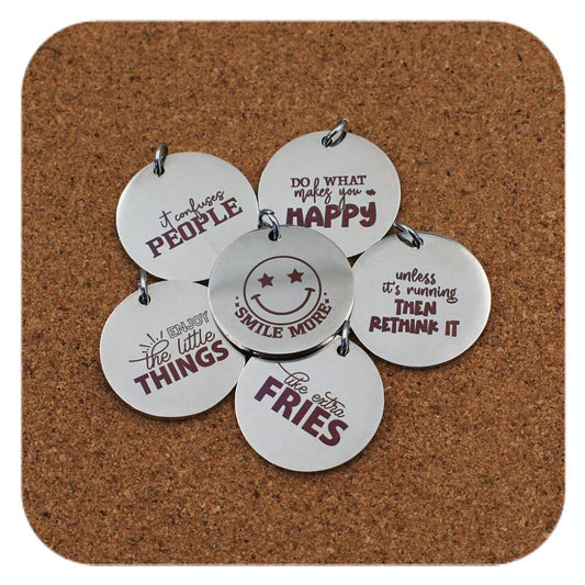 Silver pendants with different Smiles & Motivation designs on cork background