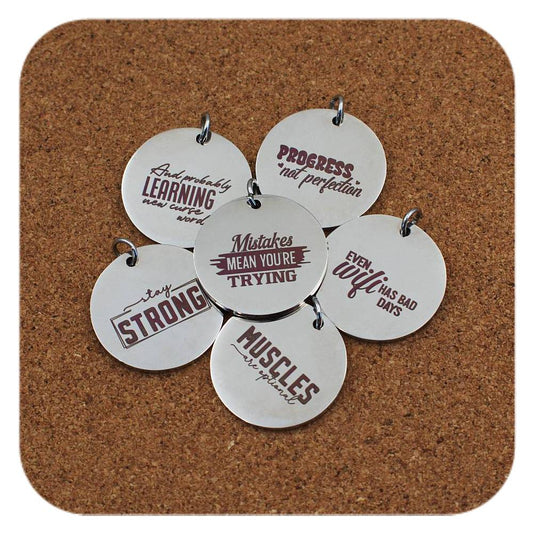 Silver pendants with different Funny Motivational Quote designs on cork background