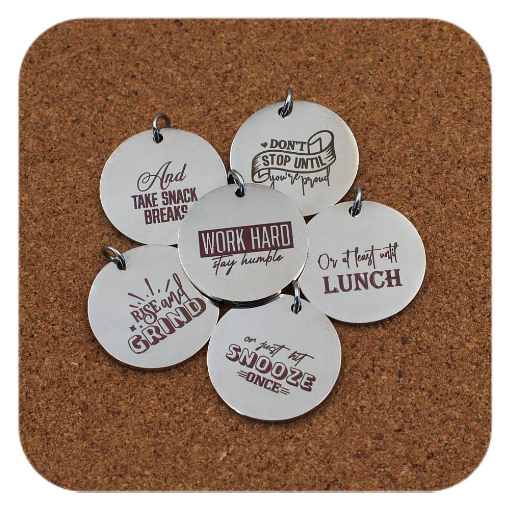 Silver pendants with different Laugh & Inspire designs on cork background