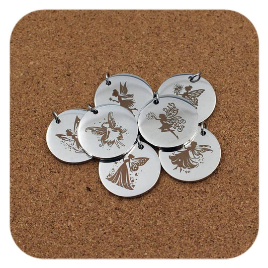 Silver pendants with different Enchanted Fairy designs on cork background
