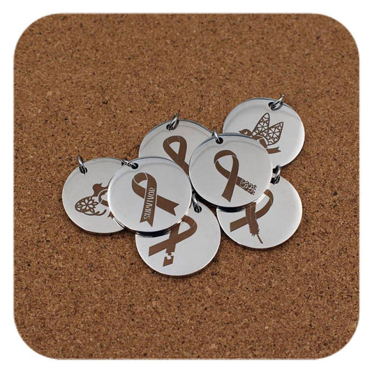 Silver pendants with different Cancer Awareness designs on cork background