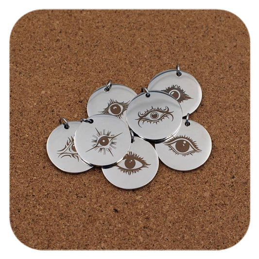 Silver pendants with different Mystic Evil Eye designs on cork background