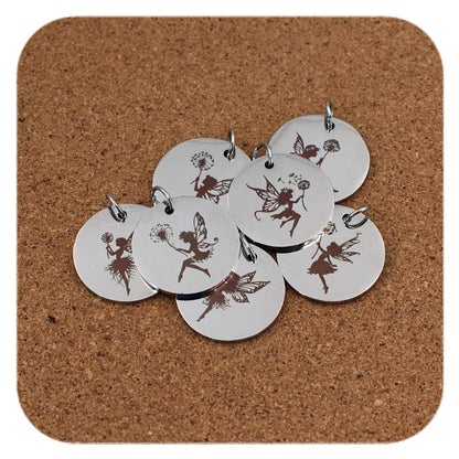 Silver pendants with different Fairy & Dandelion designs on cork background