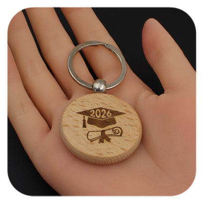 Wooden keyring with Graduation Cap Diploma 2026 design held in a hand